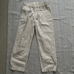 Beiga bomullsbyxor från Uniqlo M - Snygga beiga byxor från Uniqlo i 100% bomull. De har elastisk midja, köpta i Japan. Kan vara mindre i storleken. Aldrig använt 