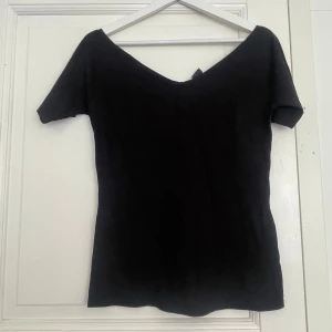 Svart v-ringad topp i bomull M - En svart, enkel och stilren topp med v-ringad hals och korta ärmar. Modellen är figurnära och passar perfekt till jeans eller kjol. Tillverkad i mjuk bomull som känns skön mot huden. Perfekt basplagg för din garderob.