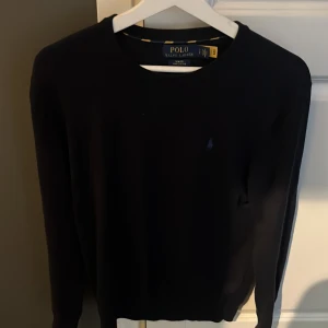 Svart tröja Polo Ralph Lauren slim fit - Svart långärmad tröja från Polo Ralph Lauren i slim fit-modell. Tillverkad i mjuk pima bomull och har den klassiska broderade loggan på bröstet. Enkel och stilren design som funkar till allt.