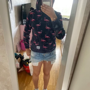 Mörkblå hoodie med flamingos från Blount & Pool - Säljer en mörkblå hoodie från Blount & Pool med rosa flamingomönster över hela tröjan. Tröjan har huva, magficka och långa ärmar. Pris kan diskuteras.