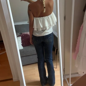 G-Star RAW Midge Bootcut Jeans - Mörkblå bootcut jeans från G-Star RAW, modell Midge. Snygg klassisk tvätt med lätt slitning, femficksmodell och låg midja. Jeansen är i stretchigt denim som sitter skönt och har dragkedja framtill.