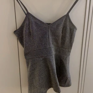 Glittrig topp - Svart silvrig glittrig peplum topp från bikbok. Stl M men passar även S