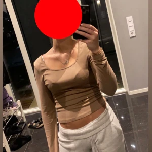 Beige croppad långärmad topp - Säljer en beige croppad långärmad topp med rundad halsringning. 