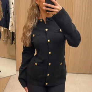 Cardigan med knappar - Stilren svart cardigan  med markerad midja och snygga guldknappar framtill. Cardiganrn har aldrig kommit till användning!