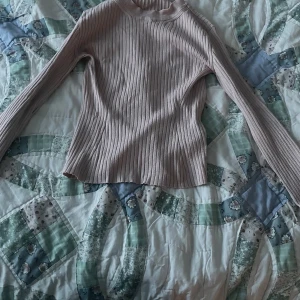 Ljusrosa ribbad långärmad tröja - Supersnygg ljusrosa ribbad tröja med lång ärm och hög hals. Tröjan är figurnära och har en mjuk, stretchig känsla som passar perfekt till jeans eller kjol. Enkel men ändå trendig med sitt ribbade mönster.