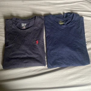 Två mörkblå t-shirts från Polo Ralph Lauren - Säljer två mörkblå t-shirts från Polo Ralph Lauren. Ena t-shirten har en röd broderad logga på bröstet, båda har rund hals och är i mjuk bomull. Perfekta för en avslappnad stil. Tryck ej köp nu