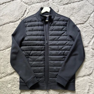 Dressmann cardigan - Säljer en mörkblå cardigan från Dressmann med dun framsida och slät baksida. Jackan är som ny och perfekt för kyliga dagar när du vill ha en stilren look!