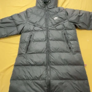 Svart lång dunjacka från Nike - Säljer en svart lång dunjacka från Nike med Storm-FIT-teknologi. Jackan har dragkedja framtill, två stora fickor med dragkedja och huva. Perfekt för kalla dagar när du vill hålla dig varm och bekväm. Nya modellen äkta och priset diskuteras, köpt för 2600 och har kvitto 