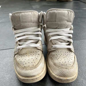 Nike Air Jordans mid  - Säljer ett par Nike Air Jordans med högt skaft och vita snören. Skorna är tillverkade i skinn och har perforerade detaljer på tån samt klassisk Nike-logga på sidan. 