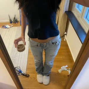 Ljusblå slitna jeans från True Religion - Säljer en ljusblå lågmidja jeans från True Religion. Som du kan se finns 2 hål under bakfickan annars en riktigt fin. Storlek W27 L32