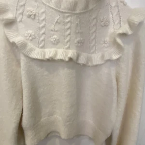 Vit stickad tröja med volang och små blommor från & Other Stories - Supersöt vit stickad tröja från & Other Stories Paris Atelier. Tröjan har volangdetaljer och ett fint mönster med små blommor och flätor upptill. Så fin men jag köpte den utan att prova först och den passar inte! 