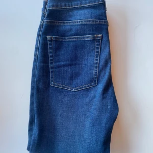 Blå jeansbyxor från Acne Studios - Snygga blå jeans från Acne Studios med klassisk femficksdesign och raka ben. Jeansen har normal passform och är tillverkade i ett slitstarkt denimtyg med synliga kontrastsömmar och knappstängning framtill.