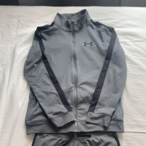 Grå under armour set strl XS - Mycket bra grå under armour set. Funkar till användning när man ska träna eller bara en vanlig dress. Den har även svarta ränder i sidan. 