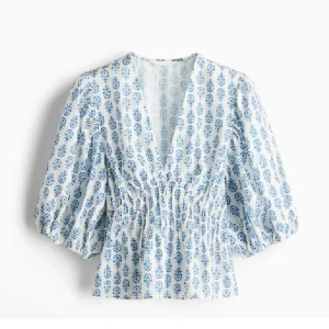 Vit och blå blus med mönster - Säljer en söt blus i vitt med blått mönster och v-ringning. Blusen har trekvartsärmar med lätt puff och smockad midja som ger en fin passform. Perfekt för vår och sommar!
