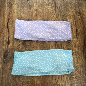 Pastellfärgade bikinitoppar med blommönster - Två bikinitoppar i pastellfärger, en lila och en ljusblå, båda med vita små blommor över hela tyget. 