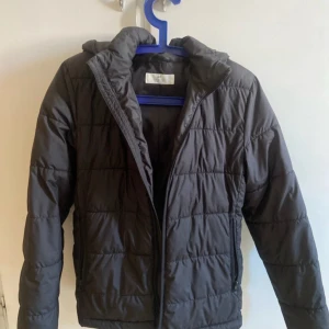 Svart pufferjacka  - Säljer en svart pufferjacka från H&M med huva och dragkedja. Inga fläckar/hål eller lukt