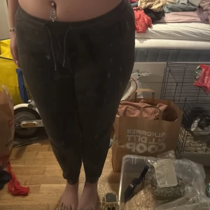 Mörkgrå mjukisbyxor från Female Passion - Mysiga mörkgrå mjukisbyxor från Female Passion med dragsko i midjan och ribbade muddar vid bensluten. Byxorna har en klassisk passform och är perfekta för en avslappnad stil.