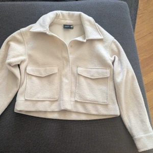Beige jacka från  - Säljer en beige jacka från Vero moda med två stora fickor framtill och krage.  