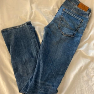 Blå bootcut jeans från Denim - Säljer ett par blå bootcut jeans från Denim. Jeansen har låg midja, fickor och snygga kontrastsömmar. Perfekta för dig som gillar en tidlös denimlook. Orginalpris- 499kr