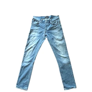 Ljusblå Nudie Jeans - Tja! Säljer dessa feta ljusblå jeans från Nudie jeans med snygga urtvättningar. Använt fint skick, lagad skada i grenen, därav priset. I modellen Grim Tim (Slimfit). Han på bilden ca 180 lång, ca 70kg, har vanligtvis W29/W30 och L34. Skriv vid minsta fundering, priset är självklart inte ristat i sten🤩🤩🤩
