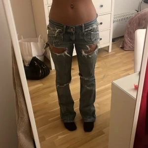 Blå slitna jeans - Säljer ett par blå jeans med slitningar och hål. De har en låg midja och bootcut-stil. Midjemått rakt över är 37 och jag är 166 för referens
