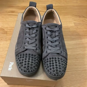 Gråa sneakers från Christian Louboutin - Säljer mina äkta louboutins med spikar. Dustbag kvitto och verifieringskort från louboutin medföljer i köpet samt box.