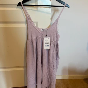 Lila klänning från Zara - Lila klänning från Zara. Denna är helt oanvänd men prislappen på och köptes för många år sen så det finns inte att hitta längre. Storleken är M men skulle även kunna passa någon som har S.