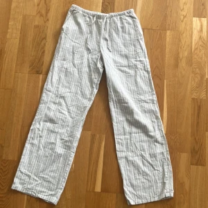 Randiga linnebyxor från Gina Tricot - Luftiga och bekväma linnebyxor från Gina Tricot i ljusgrått med vita ränder. Byxorna har vida ben. Perfekta för varma dagar eller bara för en avslappnad stil, använt bara ett fåtal gånger💕köpare står för frakten själv 