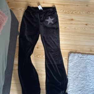 Svarta velourbyxor med strass-stjärna från SHEIN - TAR endast emot SWISH! ✅Svarta mjuka velourbyxor från SHEIN med en stor stjärna i strass på ena höften. Byxorna har resår i midjan och är raka i modellen men utsvängda, perfekta för en trendig och bekväm look. 
