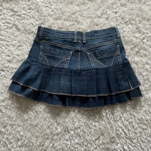 Mörkblå jeanskjol med volanger - Jeanskjol med volanger omsydd från ett par jeans.  Midjemått tvärsöver -40cm Längd - 35cm