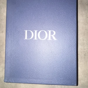 Svarta sneakers från Dior - Säljer ett par svarta Dior-sneakers med vita detaljer och reflekterande partier. Skorna har en chunky sula, snörning och meshpaneler för extra andningsförmåga. Perfekta för dig som vill ha en lyxig och sportig look.