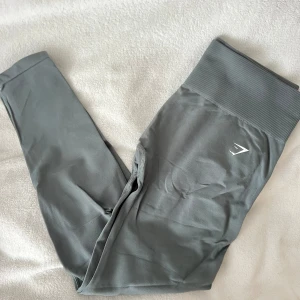 Gråa tights från Gymshark - Snygga gråa tights från Gymshark med hög midja och diskret logga på låret. Tightsen har en tight passform och bred ribbad linning som ger extra stöd. 