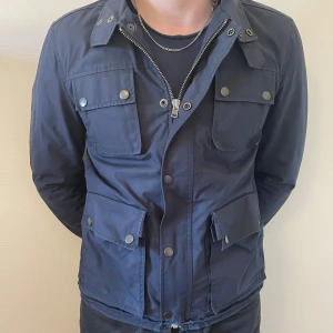 J Lindberg Field Jacket - Säljer denna tvär snygga jackan från J Lindberg i storlek M då det inte har kommit till användning, min kompis på bilden är 186cm lång och väger c.a. 80kg. Den har tyvärr två trasiga knappar vid fickorna men det är inte synligt  - tvivla inte att höra av er ifall ni har frågor! 