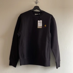 Helt ny Carhartt sweatshirt, svart, XS - Säljer en helt ny sweatshirt från Carhartt i storlek XS. Prislapp kvar. Tröjan är svart, har rund halsringning, långa ärmar och en liten broderad Carhartt-logga i gult och rött på bröstet. Tillverkad i bomull och polyester för en mjuk och bekväm känsla. Nypris ca 1250 kronor.