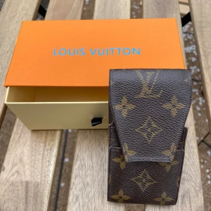 Louis Vuitton miniväska - Den klassiska lilla väskan, ibland cigarrettetui.  Köpt på Campadre ViP-auktion för 10 år se . Kvitto finns på sista bilden. Extremt sparsamt använd och man ser inga spår av användning. Lådan kan va ihopblandad med annan LV produkt.