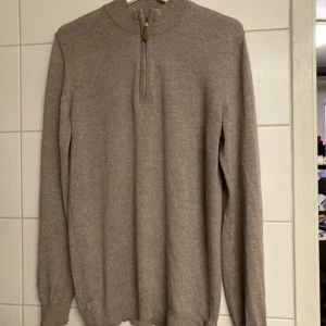 Beige merinoulltröja från Stenströms - Säljer en stilren beige tröja från Stenströms i 100% merinoull. Tröjan har en dragkedja vid halsen och långa ärmar. Perfekt för kyligare dagar med sin mjuka och varma känsla.