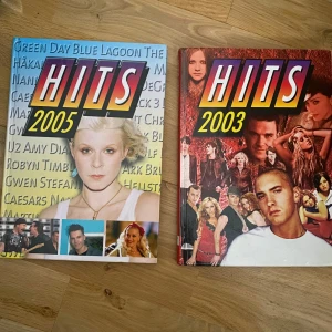 HITS 2003 & HITS 2005 - Två samlingsböcker med titeln HITS från åren 2003 och 2005. Omslagen pryds av kända artister och band från respektive år, med färgstarka collage och stora titlar. Perfekt för dig som gillar pop- och rockmusik från tidigt 2000-tal. Noter/ackord/text fint skick 