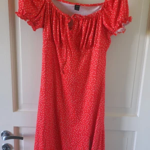 Röd prickig klänning från SHEIN - Superfin röd klänning med vita prickar från SHEIN. Klänningen har korta puffärmar, söt knytning vid halsen och en luftig passform. Perfekt för sommardagar och har en romantisk vintagekänsla.