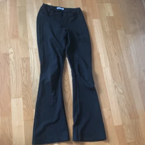 Svarta bootcut-byxor från Name It - Svarta byxor från Name It i bootcut-modell. Byxorna har en mjuk och stretchig känsla med resår i midjan för extra komfort. Perfekta för dig som gillar en klassisk och enkel stil med lite utsvängda ben.