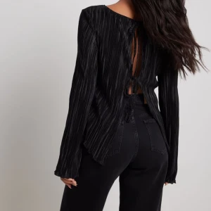 Svart långärmad topp med snörning i ryggen - Säljer denna populära topp från Nakd!! Långärmad topp med knytningar i ryggen, lite glansig i materialet vilket ger ett lyxigt intryck! Tunn i matierialet så perfekt till sommarens fina tillfällen! Nypris 399kr