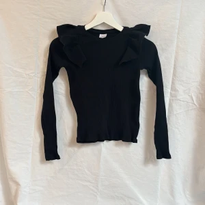 Svart ribbad tröja med volangdetaljer från Zara - Säljer en svart långärmad ribbad tröja med volanger från Zara