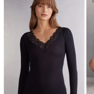 Svart långärmad topp med spets - Snygg svart långärmad topp med djup v-ringning och dekorativ spetskant runt halsen. Perfekt att styla till både jeans och kjol för en trendig look från Intimissimi. Den är i M men oxå känns som S