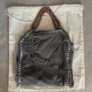 Stella McCartney väska  - Säljer min gråa Stella McCartney väska. Den har en defekt, 3 bilden men inget som syns. Väskan är mer ljus grå i verkligheten. Man får med dustbag