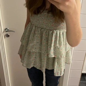 Grön blommig topp/kjol från Bubbleroom - Söt grön topp/kjol med blommigt mönster från Bubbleroom i nyskick! Kjolen har en volangdetalj och en elastisk midja för bekväm passform. Perfekt för en somrig look!🌸OBS: Är stor i storleken.
