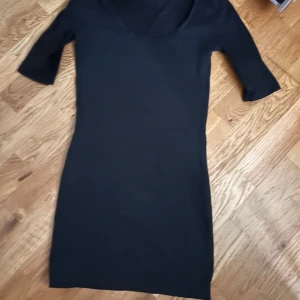 Svart tight klänning med u-ringning - En svart tight klänning med u-ringning och halvlånga ärmar. Enkel och stilren design som passar perfekt till många tillfällen. Klänningen har en kroppsnära passform.