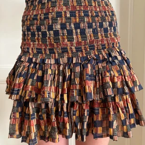 Mönstrad volangkjol - Kort volangkjol med elastisk midja och färgglatt mönster i blått, orange, rött och gult. Kjolen har flera lager volanger och ett ”rutigt”mönster. Kommer från Isabel Marant. Ingen storlek men skulle säga XS/S