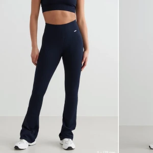 Mörkblå ribbade mjukisbyxor - Säljer ett par mörkblå ribbade tajts med hög midja och utsvängda ben. Byxorna är stretchiga och har en bekväm passform, perfekta för en avslappnad stil eller träning.