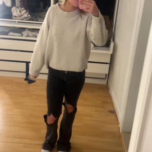 Beige stickad tröja med pärlor - Säljer en beige stickad tröja med pärldetaljer. Tröjan har rund halsringning och långa ärmar. Perfekt för dig som vill ha en mysig och stilren look.