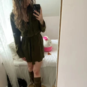 Khaki skjorta/ klänning  - Khaki/ grön skjorta/ klänning från H&M i storlek 34💕 knäpps med två knappar i midjan och kan knytas som man vill med bandet i midjan💕 slits på sidorna💕 Liten fläck på ärmen (sista bilden) inget som märks💕