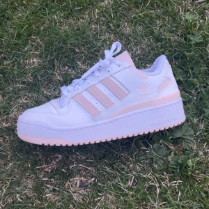 Vita och ljusrosa Adidas sneakers - Säljer ett par snygga Adidas sneakers i vitt och ljusrosa. Skorna är knappt använda och i väldigt bra skick, nypris 1349💕